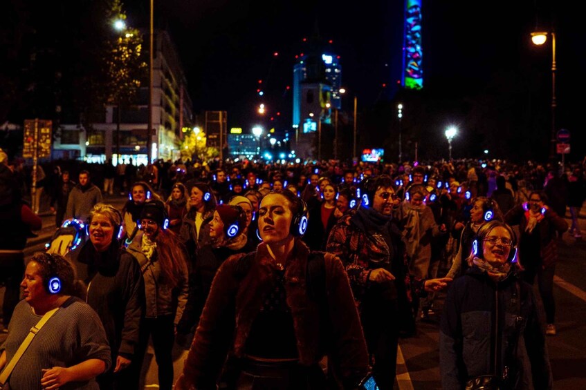 A crowded street at night with many people wearing headphones. 1