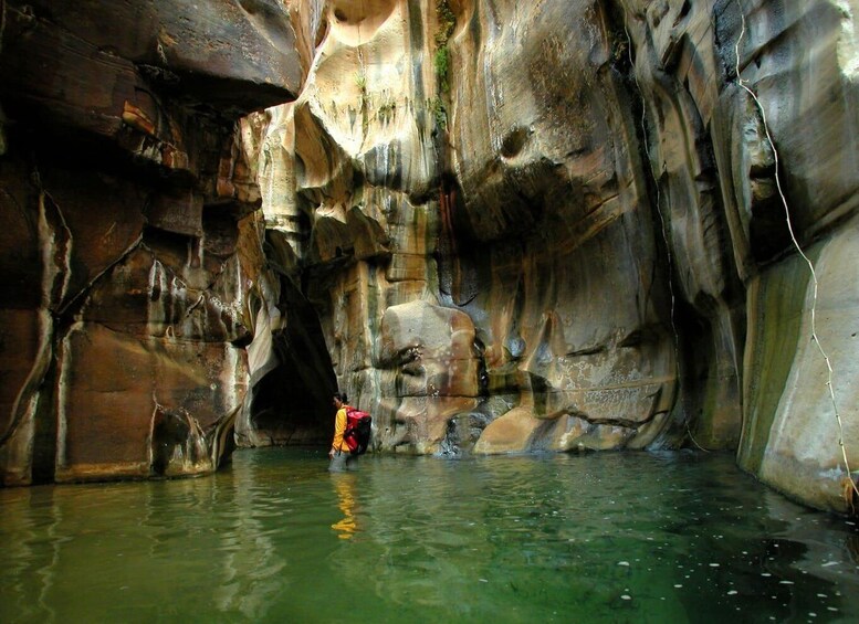 A person in a cave with water at the bottom. 1