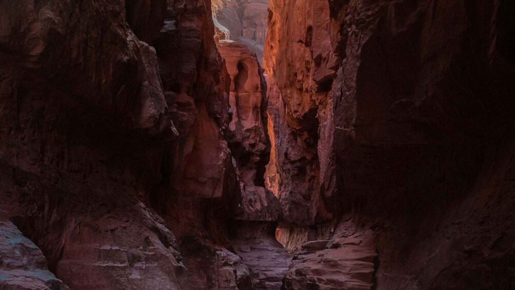A canyon with steep, reddish rock walls and a narrow passageway. 2