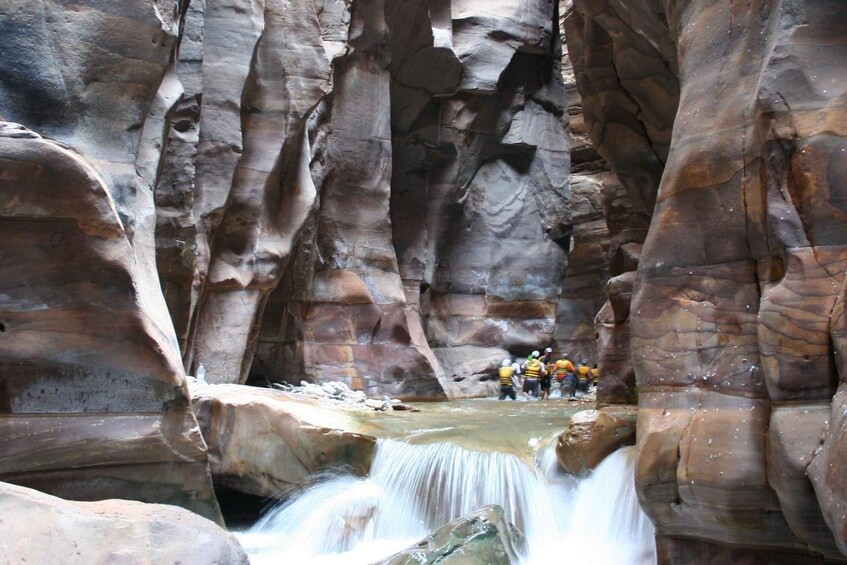A waterfall in a canyon with people standing on a ledge. 4