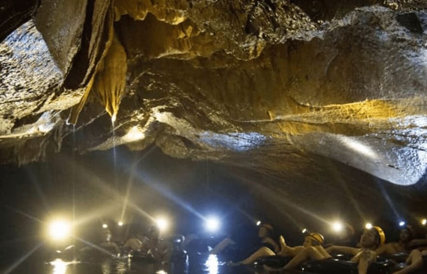 A cave with stalactites and a group of people swimming in a pool. 5