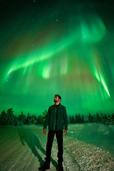 A person standing on a road with the Northern Lights in the background. 4