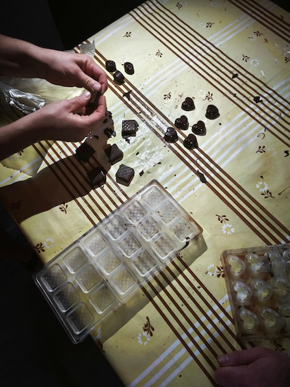 A person placing chocolate pieces into a mold. 2