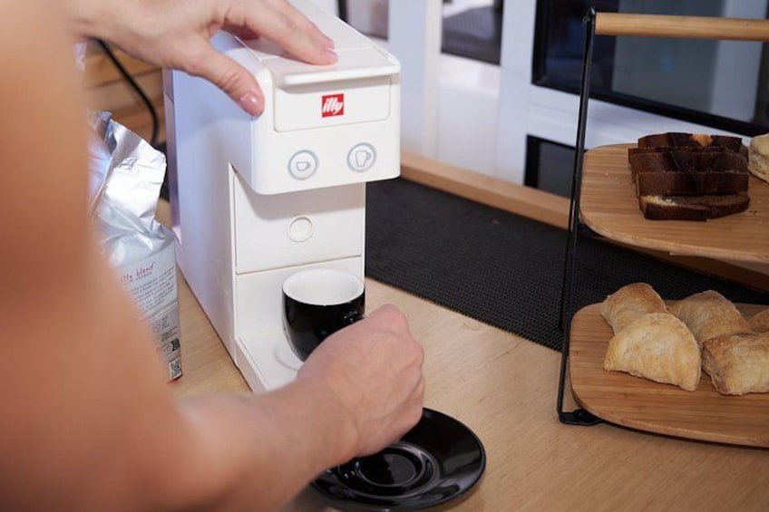En person betjener en kaffemaskine med en kop på disken. 4