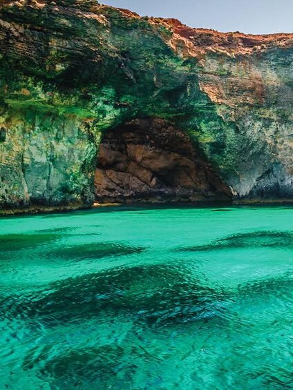 Mar turquesa y cristalina, un acantilado rocoso y la entrada de una cueva. 3