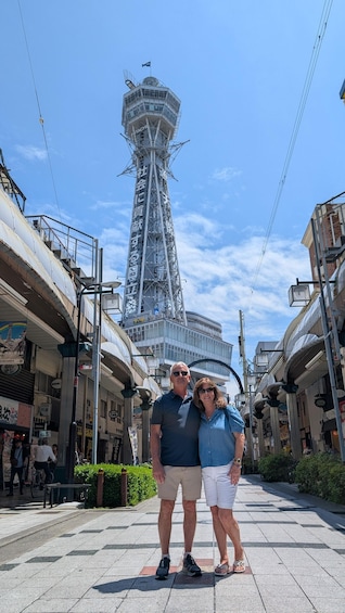 A couple standing in a pedestrian area with a tall tower in the background. 2
