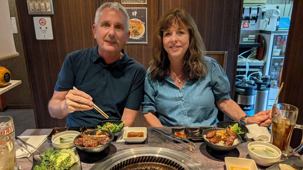 Two people dining at a restaurant with various dishes and drinks on the table. 4