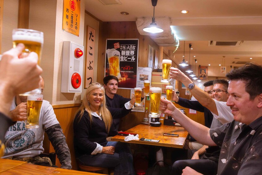 A group of people toasting with beer glasses in a restaurant. 1