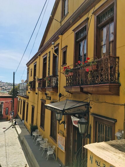 A yellow building with balconies, outdoor seating, and a street view. 4