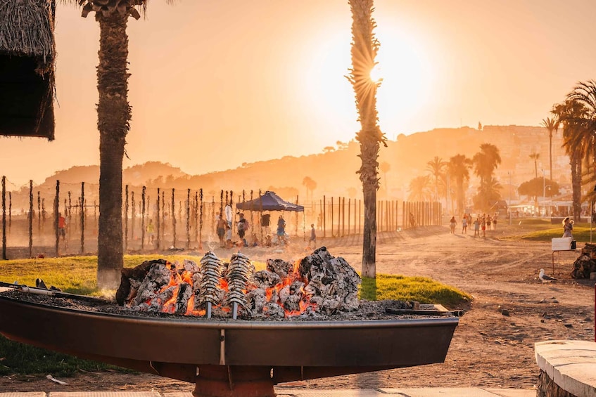 A barbecue grill with flames, palm trees, and a sunset in the background. 5