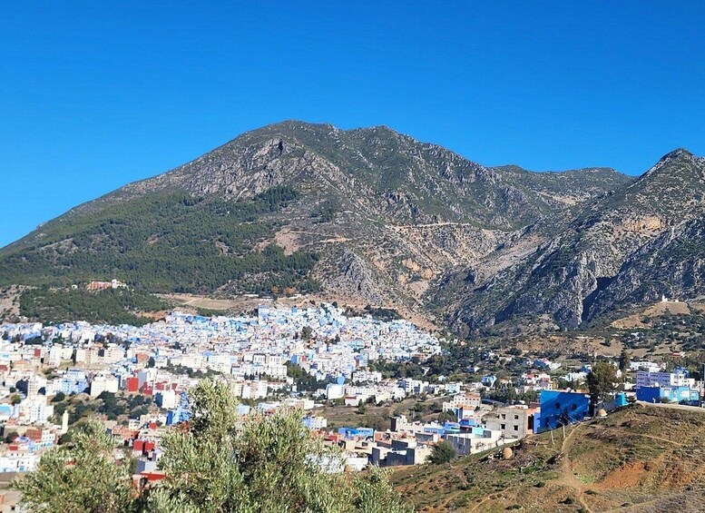 A town with blue and white buildings nestled in a valley, surrounded by mountains. 4