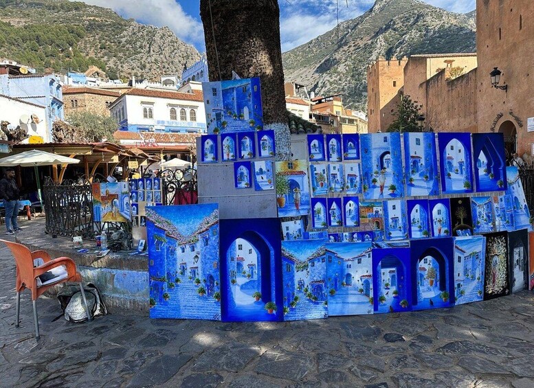 A street with blue-painted buildings and a tree in the foreground. 2