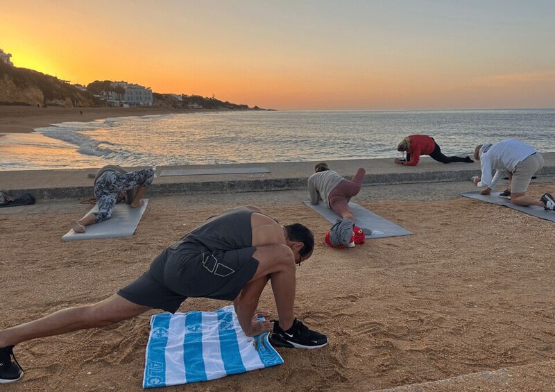 People doing yoga on mats at a beach during sunset. 4