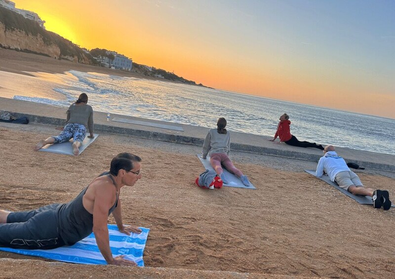 People exercising on mats at a beach during sunset. 5