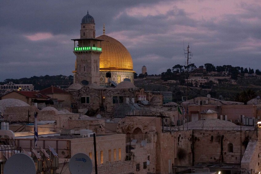 A historic building with a large dome and a minaret, surrounded by residential structures. 1