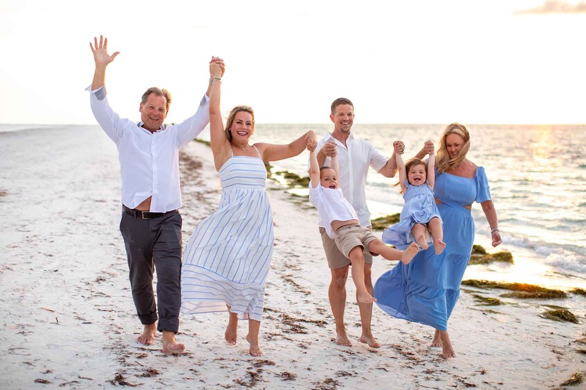 A family walking on a beach with the ocean in the background. 5