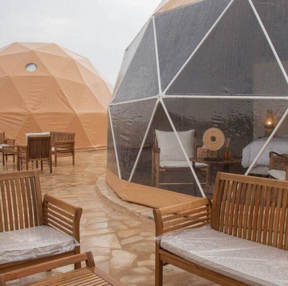 A geodesic dome structure with a seating area inside. 1
