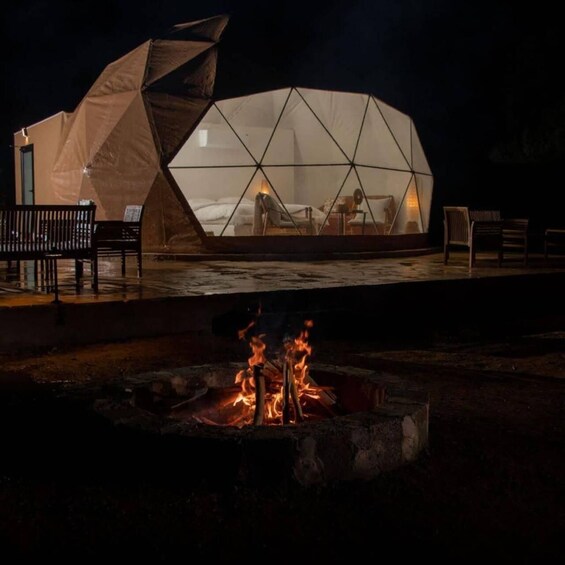 A geodesic dome structure with a fire pit in front. 5