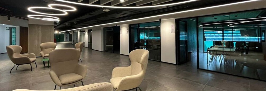 A modern office space with circular light fixtures, beige chairs, and glass walls. 2