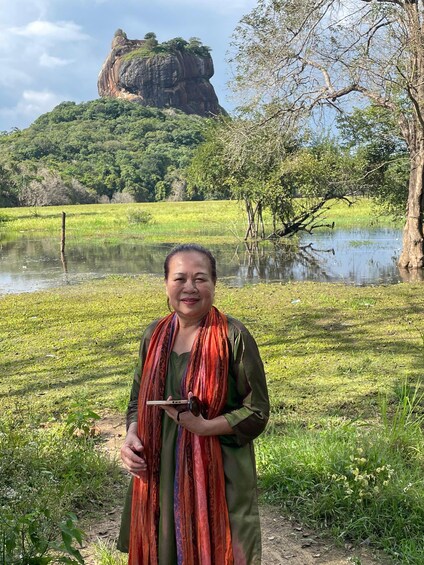 A person standing in a field with a large rock formation in the background. 3
