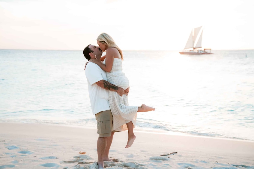 A couple embracing on a beach with a sailboat in the background. 1