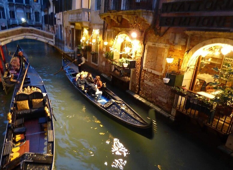 A gondola with passengers on a canal in a city at night. 4