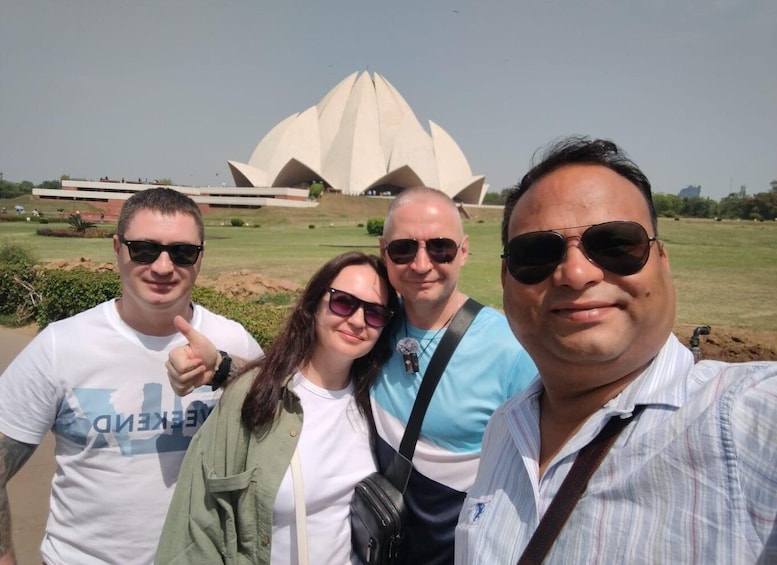 Four people posing in front of a large, white, lotus-shaped building. 1