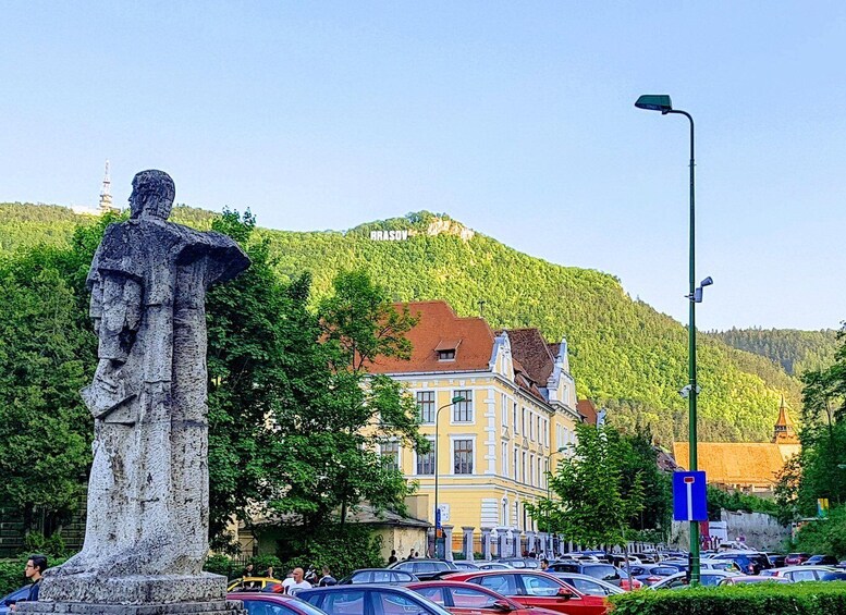 A statue, a parking lot, and a building with a red roof. 2