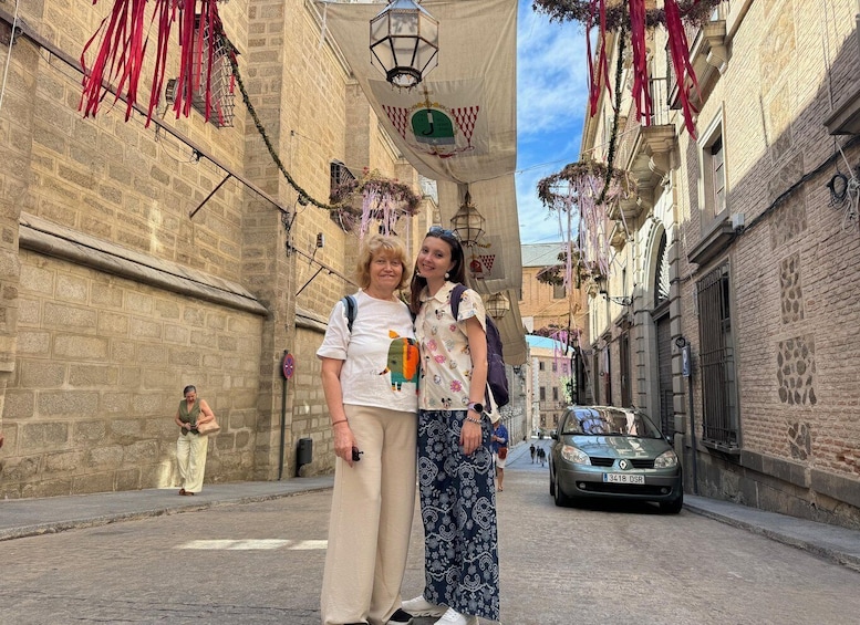 A narrow street with buildings on either side, decorated with red ribbons and hanging lanterns. 5