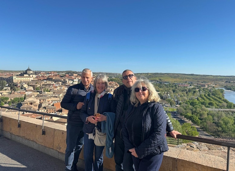 A group of people standing on a ledge overlooking a city with a river and hills in the background. 4