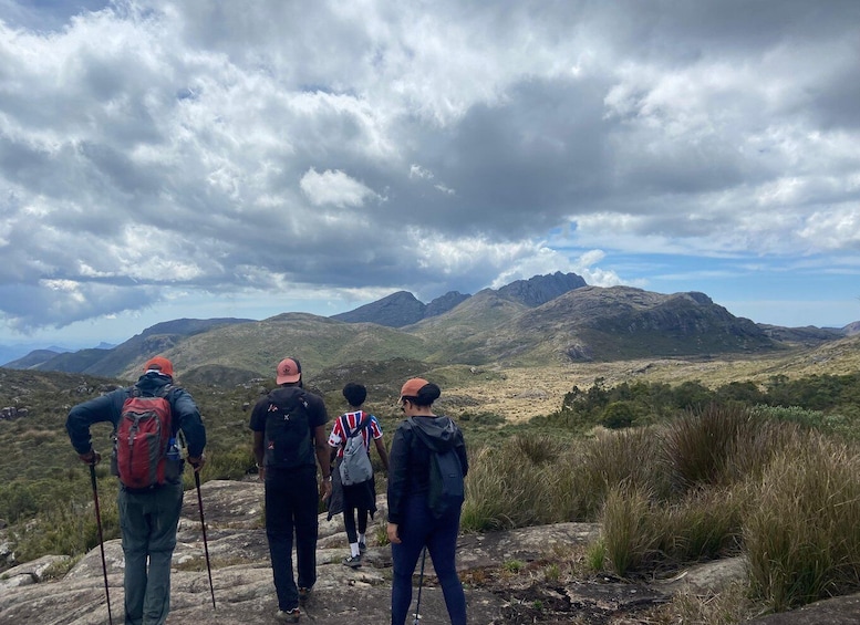 A group of hikers on a rocky trail with mountains in the background. 5