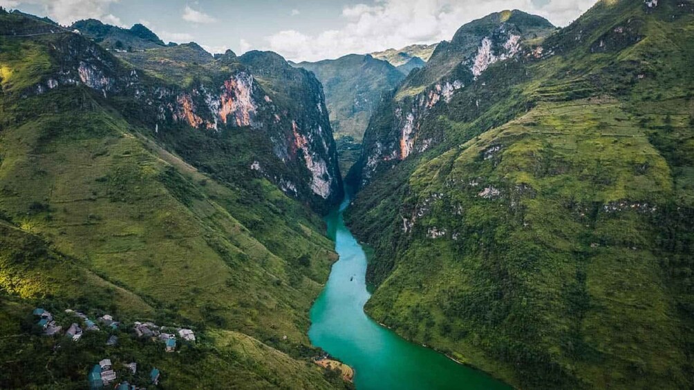 A deep valley with a turquoise river, surrounded by steep, green hills. 1