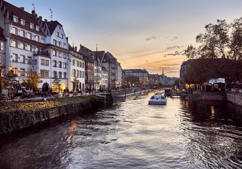 A river with a boat, buildings along the riverbank, and a sunset in the background. 4