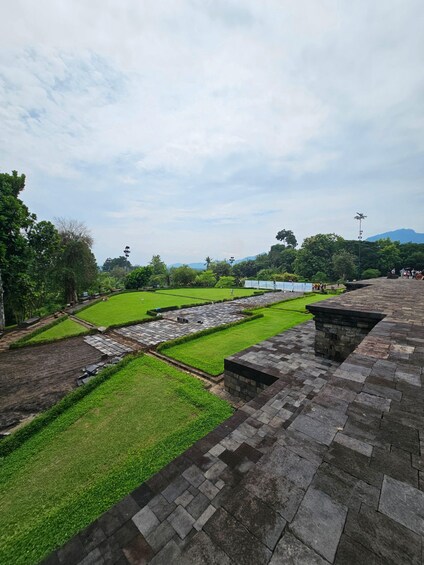 A park with stone pathways, green lawns, and trees. 2