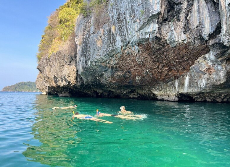A clear blue sea with people swimming and floating on a raft. 5