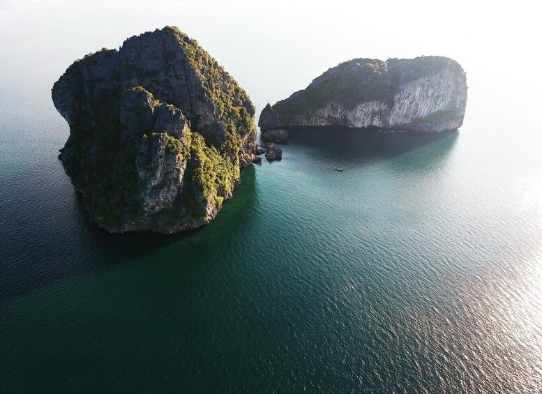 An aerial view of two large rock formations surrounded by calm water. 1