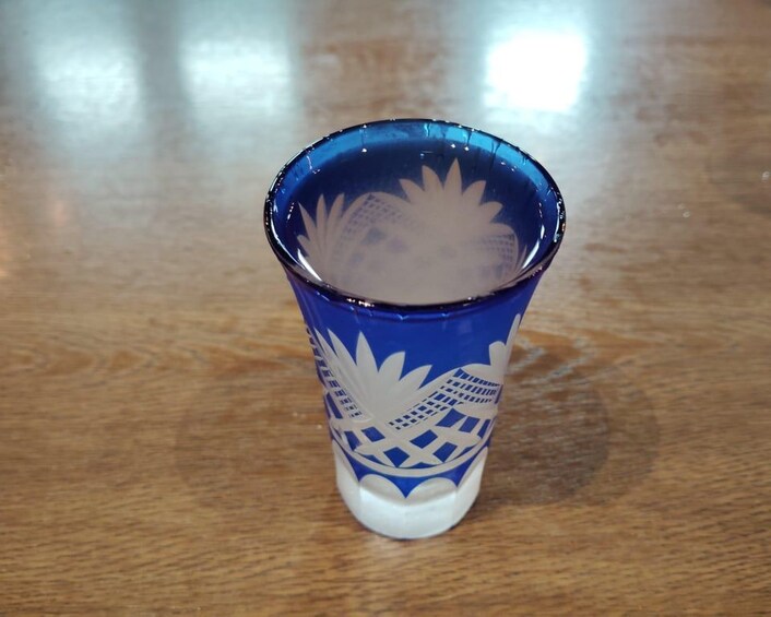 A blue glass with white patterns on a wooden surface. 5