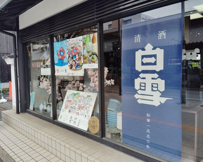A storefront with a large blue banner displaying Japanese characters and a poster advertising a beverage. 3