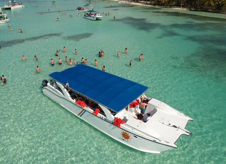 A boat with a blue canopy and red decorations on a turquoise sea with other boats and people. 3