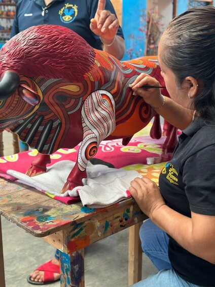 Una persona pintando un diseño colorido y con motivos sobre una tela. 2