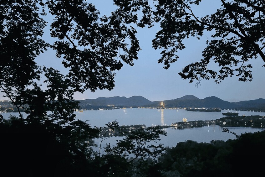 A lake with mountains in the background and a lit building in the distance. 2