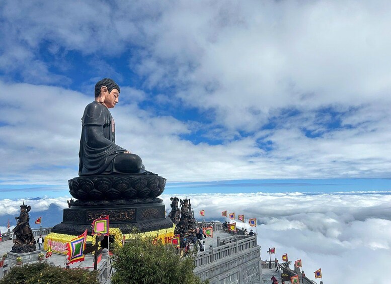 A large seated statue on a pedestal, surrounded by flags and a mountainous landscape. 1