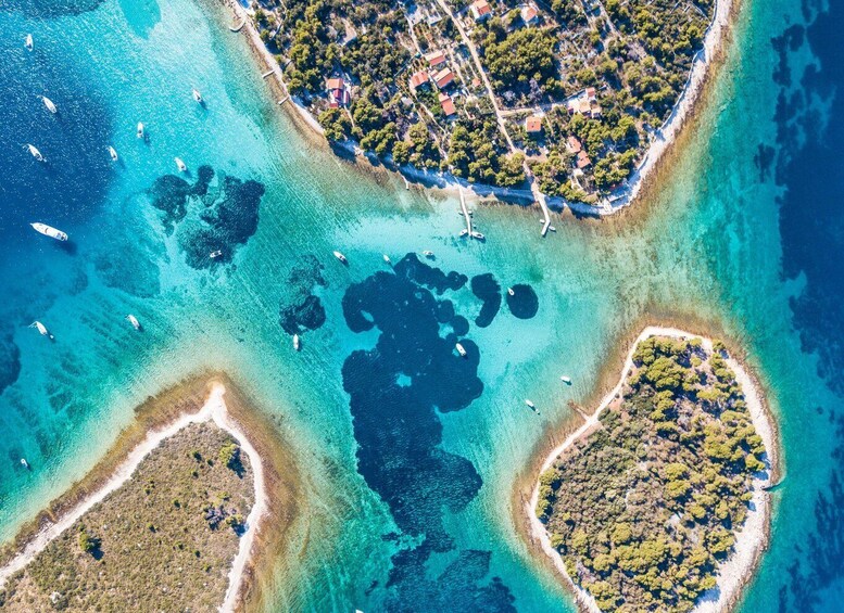 An aerial view of a coastal area with clear turquoise waters, several small islands, and a few boats. 4
