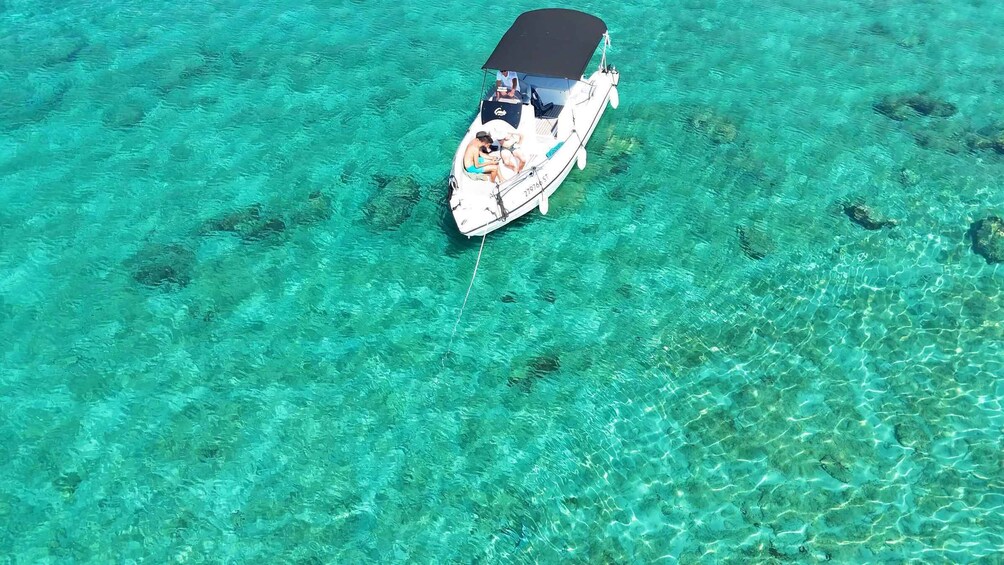 A boat with a canopy and passengers on a clear turquoise sea. 3