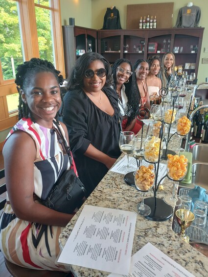 A group of people seated at a table with wine glasses and menus in a restaurant. 1