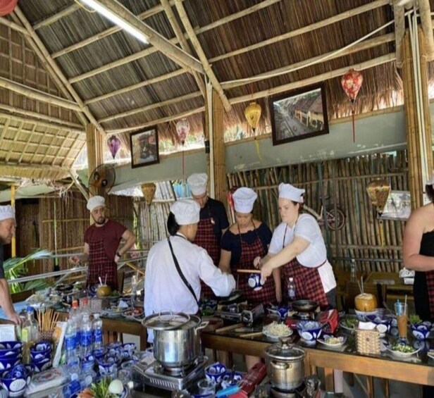 A group of chefs preparing food in a rustic kitchen with bamboo walls and a thatched roof. 2
