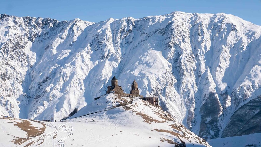 A snow-covered mountain with a historic church and two towers. 5