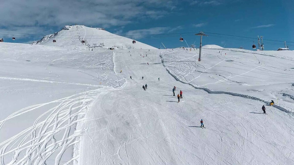 A snowy ski slope with skiers and a ski lift. 2