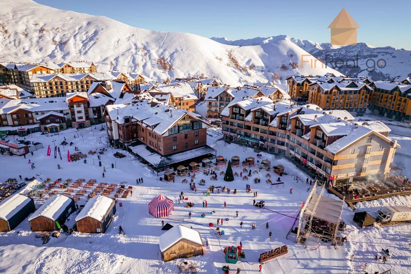 A snow-covered ski resort with buildings, a ski lift, and a mountain backdrop. 4