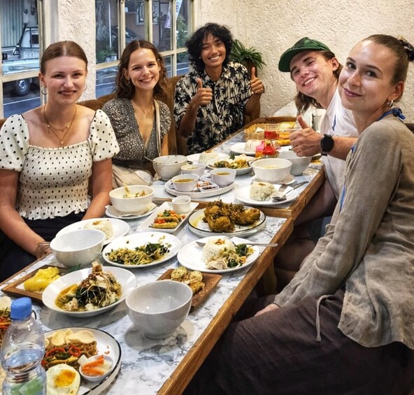 A group of people seated around a table with various dishes, including rice, vegetables, and meat. 3